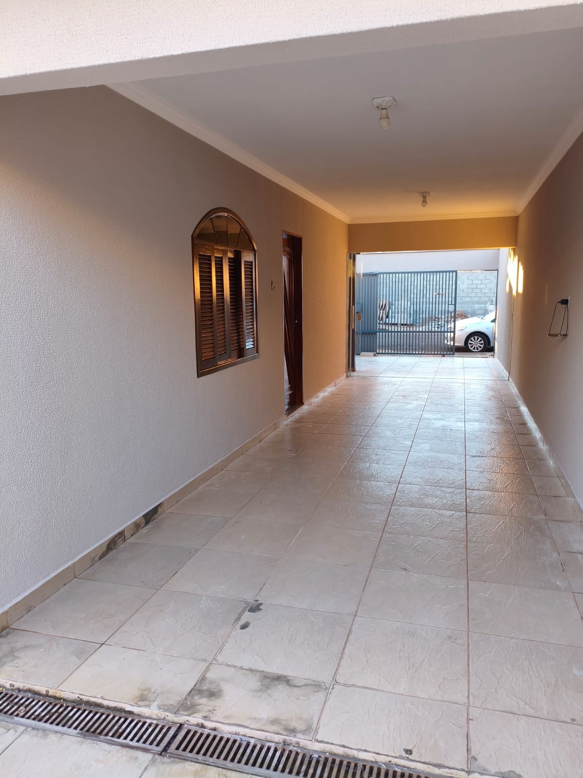 Corredor externo coberto com paredes recém-pintadas e piso de porcelanato